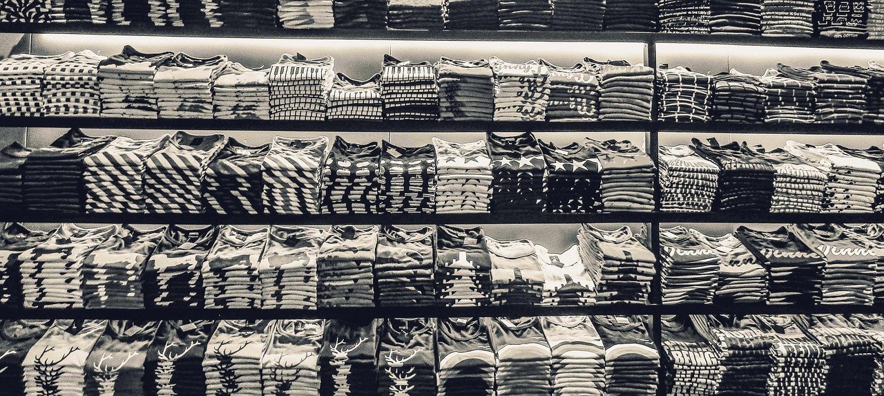 Camisetas colgadas en el perchero de una tienda: a 25 € con 14 € de coste de producto, cada unidad deja 11 € de margen bruto antes de envío, pasarela, embalaje y devoluciones